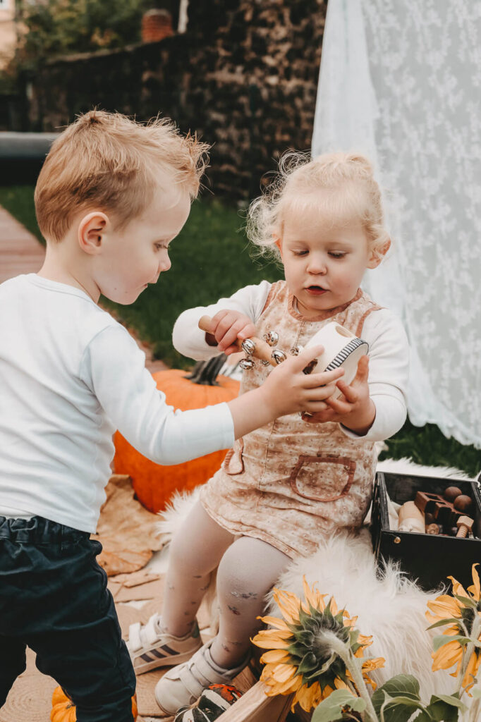 Zwillinge spielen mit Kürbissen.