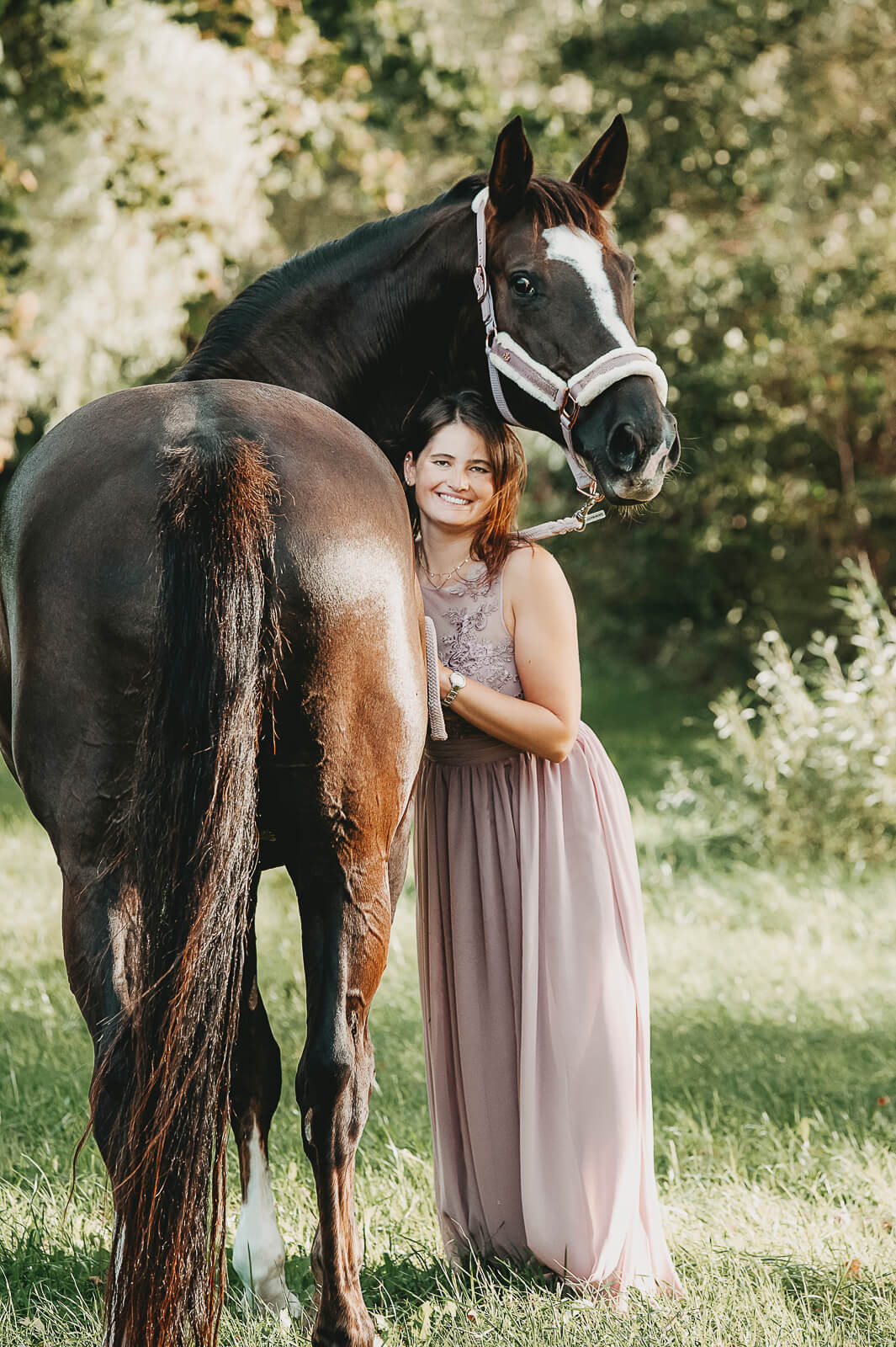 Schwarzes Pferd mit Frau im rosa Kleid
