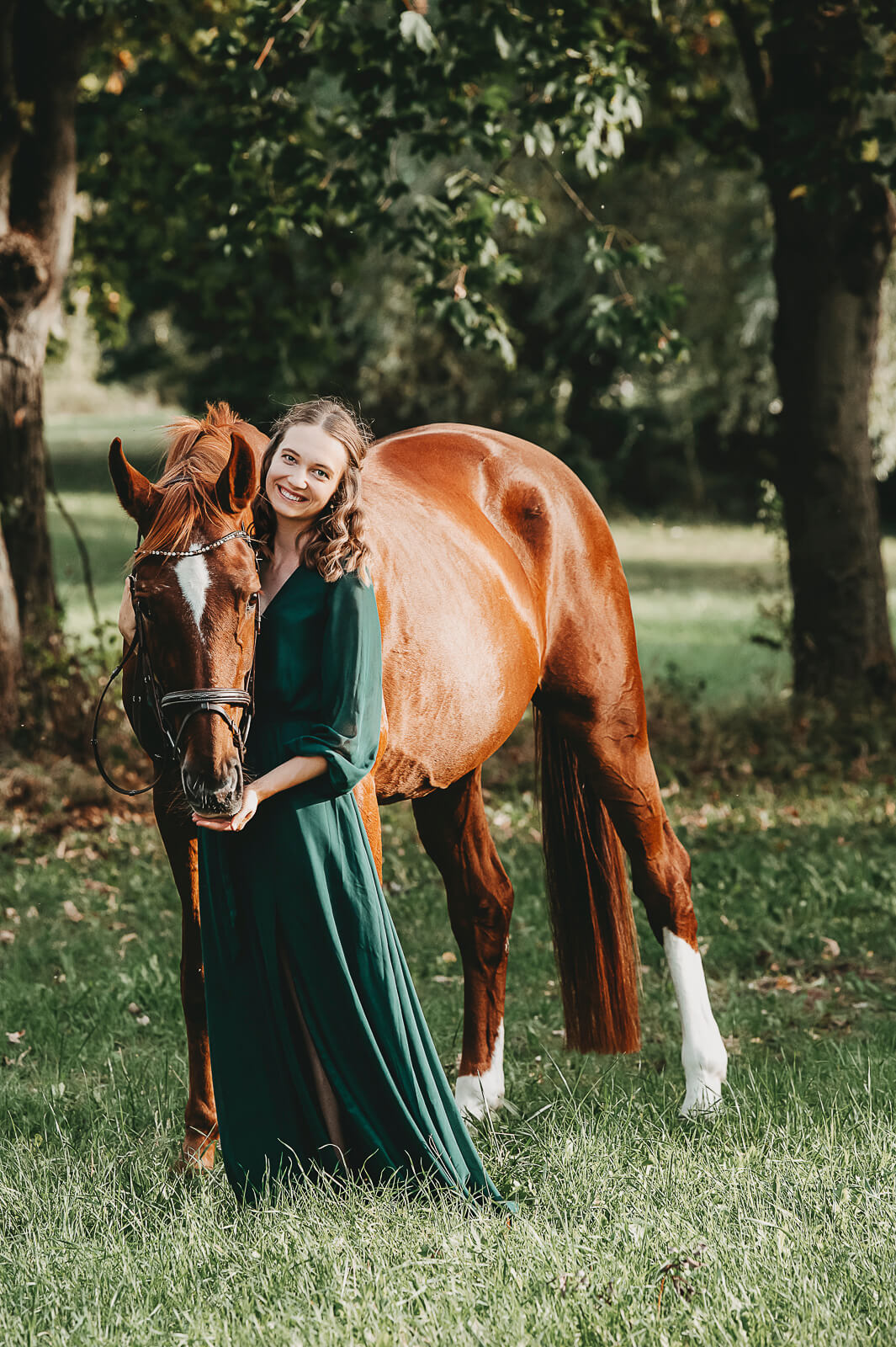 Pferd mit Frau im grünen Kleid steht auf einer Wiese. Familienfotografie Wetterau